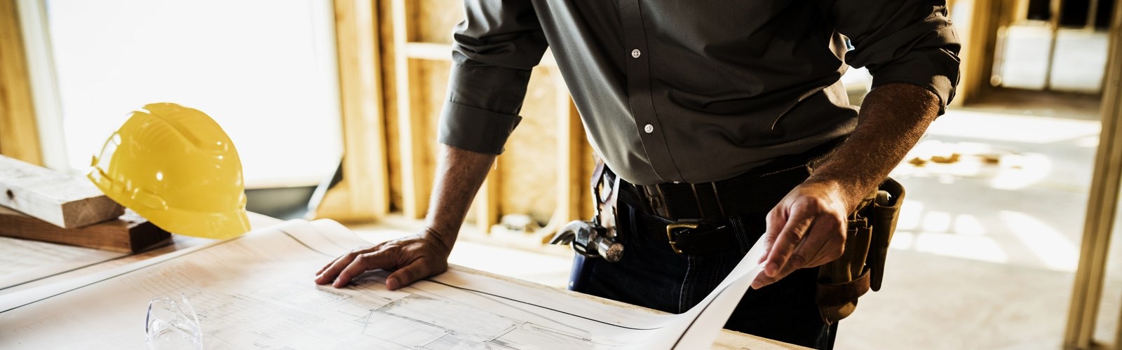 Man flipping through building plans at construction site